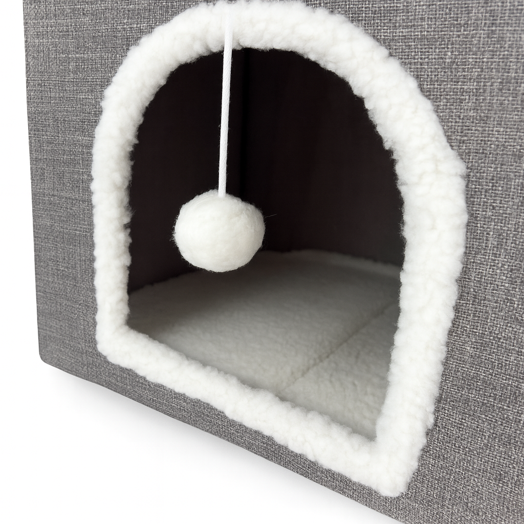 Cat bed with a white ball hanging inside on a gray background