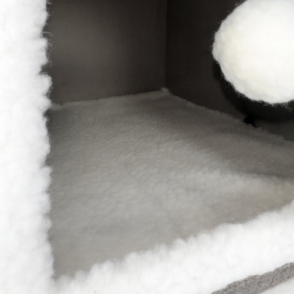 Close-up of a textured gray fabric with a white pom-pom on a light gray background